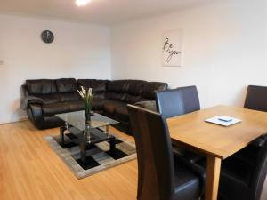 ein Wohnzimmer mit einem Ledersofa und einem Tisch in der Unterkunft 2 bed Apt on Quiet Cul-de-Sac, Fab Location in Paisley