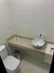 a white bathroom with a sink and a toilet at Hostel Vila dos Corais in Arraial do Cabo