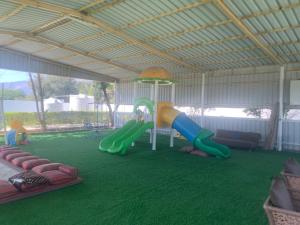 Noor Farm Stay 5BHK في خور فكان: منطقة لعب مع ملعب مع زحليقة