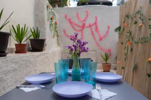 een tafel met borden en blauwe glazen en paarse bloemen bij Moon Haven Near Acropolis in Athene
