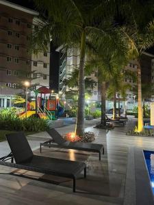 um pátio com cadeiras e palmeiras e um parque infantil em Athena's Place - Hope Residences SMDC Trece Cavite em Trece Martires