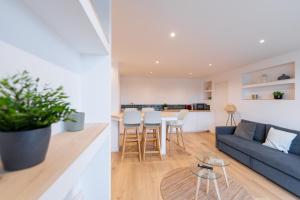 ein Wohnzimmer und eine Küche mit einem blauen Sofa und einem Tisch in der Unterkunft Appt premium Centre Château terrasse 2 chambres 6p vue exceptionnelle in Caen