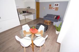 ein Wohnzimmer mit einem Glastisch und weißen Stühlen in der Unterkunft Basadre Apart Hotel in Tacna