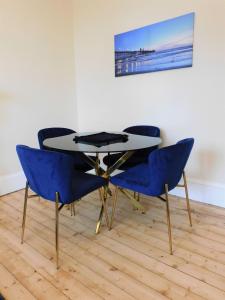 einen Tisch mit vier blauen Stühlen in einem Zimmer in der Unterkunft Beautiful & spacious 2 bed apt in Glasgow West End in Glasgow