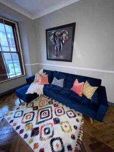 Stunning 1 bed Apt in West End في غلاسكو: غرفة معيشة بها أريكة زرقاء و لوحة فيلة