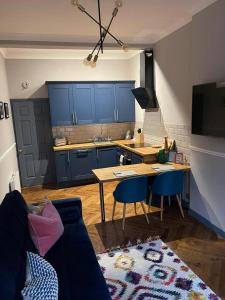 Stunning 1 bed Apt in West End في غلاسكو: مطبخ مع دواليب زرقاء وطاولة وكراسي