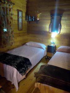 a bedroom with two beds in a log cabin at Casa La Colina Mandarina I in Tahal