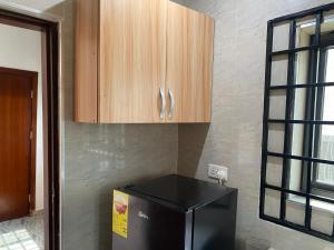 a kitchen with a black refrigerator and wooden cabinets at Arm Beach Lodge in Accra
