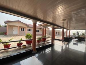 une terrasse couverte avec des plantes en pot et une maison dans l'établissement Arm Beach Lodge, à Accra