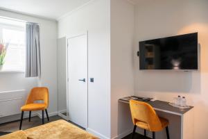 Habitación con escritorio y TV en la pared. en Hotel Grupello en Geraardsbergen