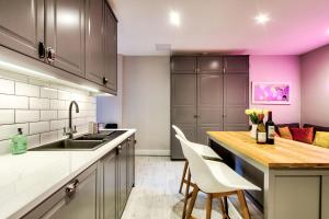 a kitchen with a sink and a table with white chairs at Stylish & Spacious 3 Bedroom Apt in Finnieston, West End in Glasgow