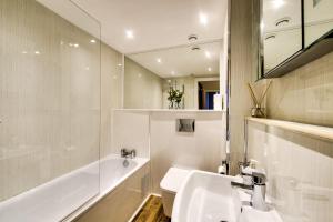 Baño blanco con lavabo, bañera y espejo en Stylish & Spacious 3 Bedroom Apt in Finnieston, West End, en Glasgow