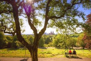 dos personas sentadas en un banco en un parque con un árbol en Stylish & Spacious 3 Bedroom Apt in Finnieston, West End, en Glasgow