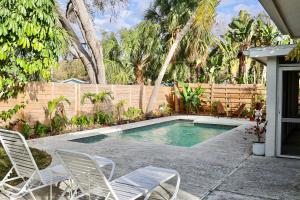 a swimming pool with chairs and a fence at Modern Oasis in Sarasota