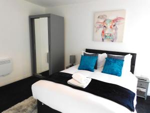 a bedroom with a large white bed with blue pillows at Newly refurbished 2 bedroom apartment close to station and local amenities in Hamilton