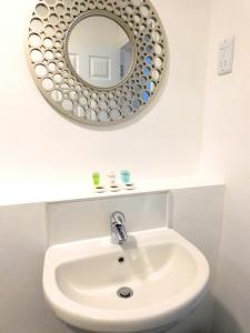 a bathroom with a white sink and a mirror at Newly refurbished 2 bedroom apartment close to station and local amenities in Hamilton