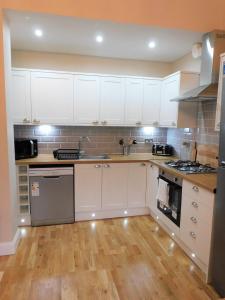 a kitchen with white cabinets and a wooden floor at Beautiful 3 bed apt in the City Centre in Glasgow