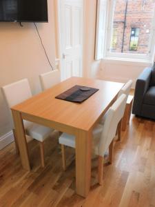 a wooden table with white chairs and a laptop on it at Beautiful 3 bed apt in the City Centre in Glasgow
