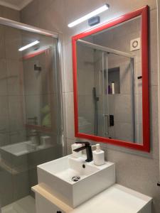 a bathroom with a white sink and a red mirror at Apartamentul Max, practic și confortabil in Oradea