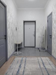 a white room with a door and a rug at Квартира in Shymkent