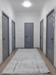 an empty corridor with three doors and a rug at Квартира in Shymkent