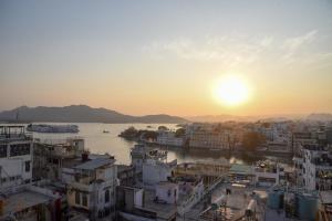 a sunset over a city with a river and buildings at Sajjan Villa in Udaipur