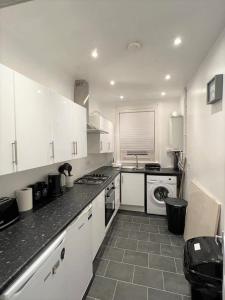 a kitchen with white cabinets and a stove top oven at Lovely 2 Bed Apt close to Silverburn Mall in Glasgow