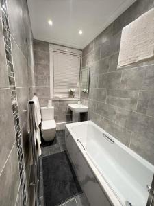 a bathroom with a tub and a toilet and a sink at Lovely 2 Bed Apt close to Silverburn Mall in Glasgow