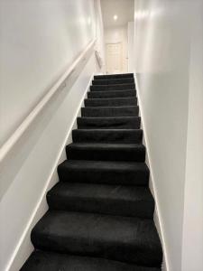 a staircase with black carpeting and a stair case at Lovely 2 Bed Apt close to Silverburn Mall in Glasgow