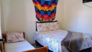 Cette chambre dispose d'un lit et d'une peinture colorée sur le mur. dans l'établissement Loft família na praia de Capri, à São Francisco do Sul