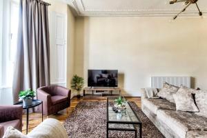 a living room with a couch and a tv at Stunning 5 bedroom apt, close to city centre, SEC, Hydro and motorway in Glasgow