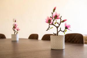 two white vases with pink flowers on a table at Stunning 5 bedroom apt, close to city centre, SEC, Hydro and motorway in Glasgow