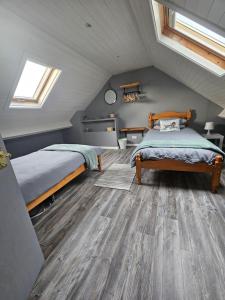 a attic bedroom with two beds and wooden floors at Kingarrow Cottage in Omagh