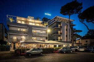 Un edificio con coches aparcados en un estacionamiento. en Appartamenti Residence Giardini CENTRALISSIMO AL MARE, en Riccione