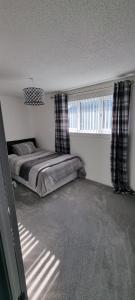 a bedroom with a bed and a window at Beautiful 2 bed house close to M74 and Strathclyde Park in Motherwell