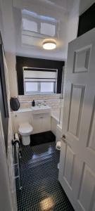 a bathroom with a toilet and a sink and a door at Beautiful 2 bed house close to M74 and Strathclyde Park in Motherwell