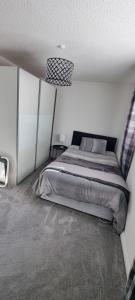 a bedroom with a bed in a white room at Beautiful 2 bed house close to M74 and Strathclyde Park in Motherwell +1 photo