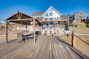 a house with a wooden deck with a table and chairs at Lakefront New London Retreat with Dock and Hot Tub! in New London