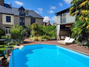 a swimming pool in front of a house at Gites Le 1900 in Val Couesnon