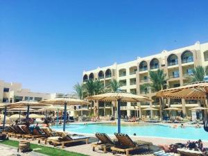 a resort with a swimming pool with chairs and umbrellas at Private 3 bdrm apartment at ElKarma Aqua Beach Reaort in Hurghada