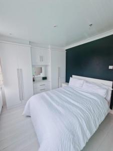 a bedroom with a large white bed with a black wall at TAAY -Luxurious 3 bedroom house in South Norwood