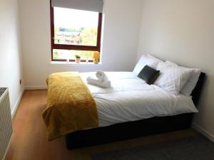 a bedroom with a bed with a yellow blanket and a window at Charming 2 bed apt close to City and SEC Hydro in Glasgow