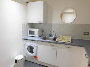 a kitchen with a washing machine and a microwave at 2 Bedroom Apt in the Heart of the City Centre, perfect Location in Glasgow