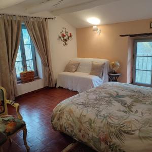 a bedroom with a bed and two windows at Le Ptit Cottage in Nyons