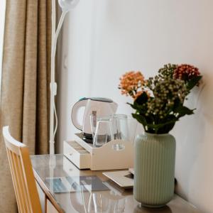 a table with a vase of flowers and a blender at Pensión mastil 16. P2 in Málaga