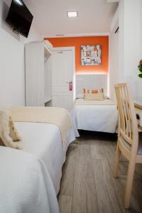 two beds in a room with an orange wall at Pensión mastil 16. P2 in Málaga