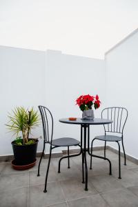 2 chaises et une table avec un vase de fleurs. dans l'établissement Pensión mastil 16. P2, à Malaga