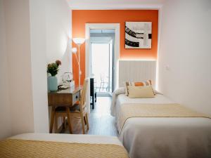 two beds in a room with orange walls and a desk at Pensión mastil 16. P2 in Málaga