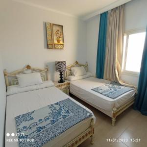 two beds in a room with blue curtains and a window at Private 3 bdrm apartment at ElKarma Aqua Beach Reaort in Hurghada
