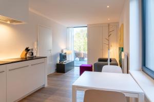 eine Küche und ein Wohnzimmer mit einem weißen Tisch und Stühlen in der Unterkunft Strandlust 21A Appartement in Wittdün